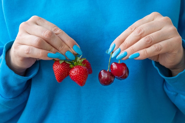 Es gibt drei Erdbeeren in einer Hand und Kirschen in der anderen