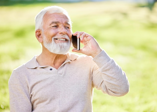 Es un hermoso día en el parque. Disparo de un anciano sentado solo afuera y usando su teléfono celular.