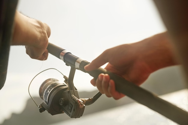 Es hora de enrollarlo Captura recortada de un joven irreconocible pescando mientras está en el mar en su bote