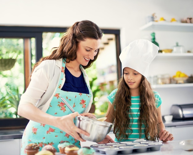 Es la hora de la magdalena Toma de una madre y su hija cocinando en la cocina