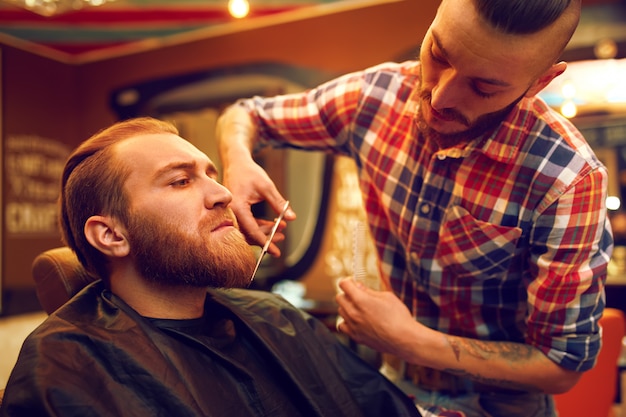 Es hora de un nuevo peinado. Apuesto joven barbudo vino al barbero para cortarse el pelo. Estilo hipster. El concepto de moda y belleza.