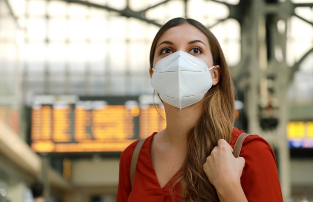 Es hora de volver a viajar. Cerca de viajero chica vistiendo KN95 FFP2 mascarilla en la estación de tren