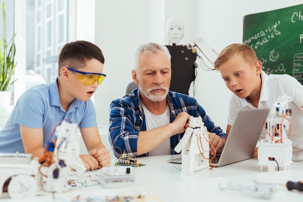 Esto es increíble. Chicos jóvenes agradables mirando la pantalla del portátil mientras muestran su entusiasmo