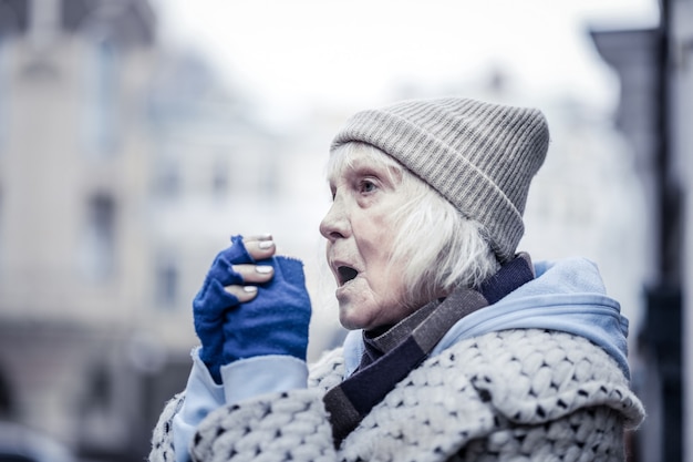 Esto es invierno. Mujer de edad deprimida que sufre de frío mientras está fuera