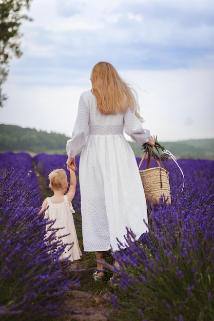 Es ist ein wunderschöner Tag in einem Lavendelfeld, während eine Mutter mit ihrer kleinen Tochter spazieren geht