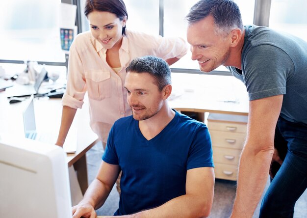 Foto es ist einfacher, als er anfangs dachte aufnahme von drei kollegen, die in einem büro auf einen computerbildschirm schauen