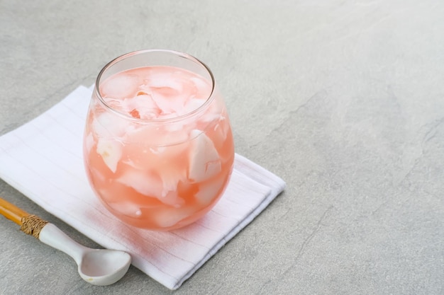 Es Kelapa Muda o bebida popular indonesia de hielo de coco joven servida en vidrio sobre fondo gris