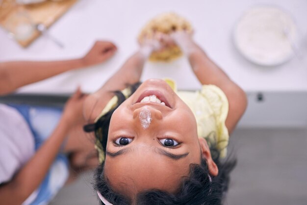 Es más feliz cuando ayuda en la cocina Captura recortada de una adorable niña horneando en casa con su madre