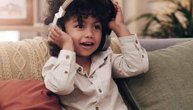 Esta es mi canción favorita Captura de un adorable niño escuchando música con audífonos mientras está sentado en un sofá en casa