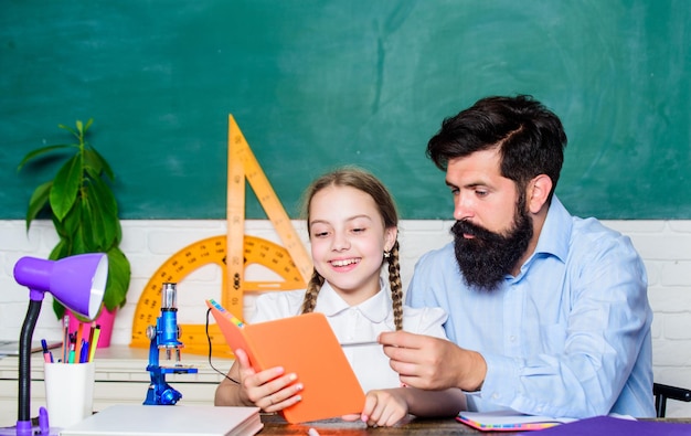 Este es mi libro. educación y conocimiento. lección de biología química. Profesor de hombre barbudo con niña pequeña en el aula. padre e hija estudian en el aula. De vuelta a la escuela. geometría matemática.