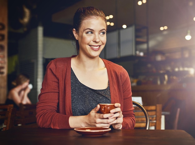 Este es, con mucho, mi café favorito Captura recortada de una mujer joven tomando una taza de café en un café