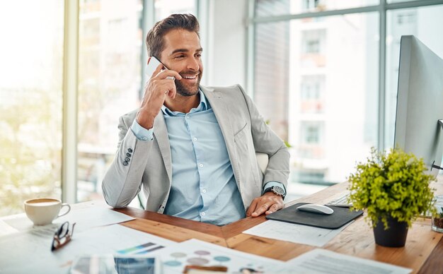 Esa es la noticia que esperaba escuchar Foto de un apuesto joven hombre de negocios hablando por teléfono celular en una oficina