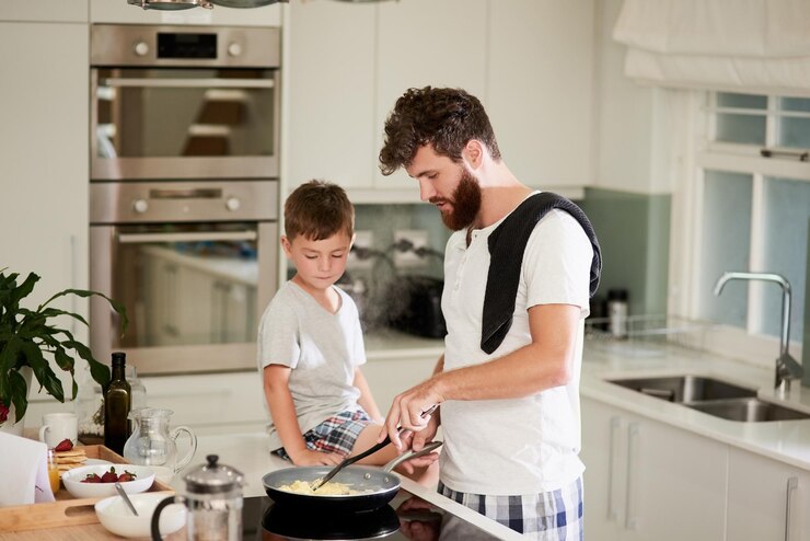Y ese es el secreto de los huevos revueltos esponjosos Fotografía de un adorable niño pequeño y su padre preparando el desayuno juntos en casa
