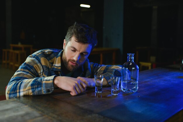 Es war ein harter Tag. Depressiver junger Mann, der Wodka in der Bar trinkt