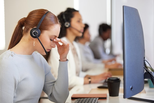 Es war ein langer Tag und ich habe null Umsatz gemacht Aufnahme einer jungen Call-Center-Agentin, die gestresst aussieht, während sie in einem Büro mit ihren Kollegen im Hintergrund arbeitet