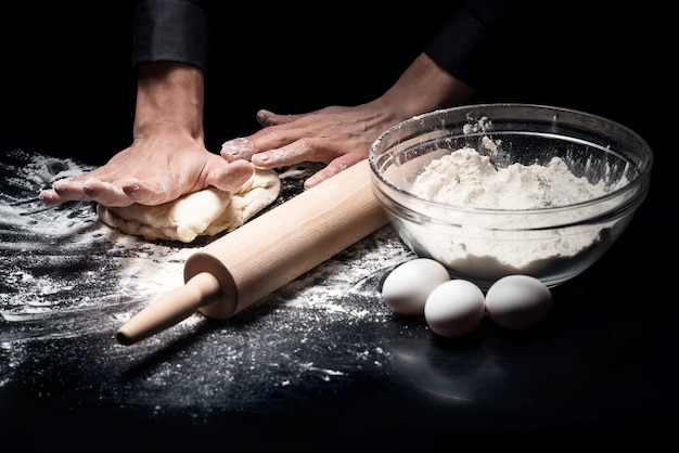 Es wird Brot. Schließen Sie oben von den Händen des Kochmanns, die den Teig kneten, während Sie in einem Restaurant arbeiten und kochen.