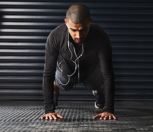 Es wird nicht einfacher, du wirst nur stärker Aufnahme eines athletischen jungen Mannes, der im Fitnessstudio Liegestütze macht