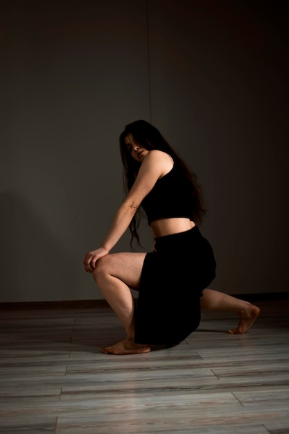 Esbelta bailarina flexible durante una práctica de danza en un estudio moderno