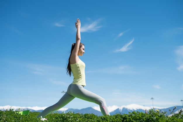 Esbelta deportista practica yoga en el parque bajo el sol medita