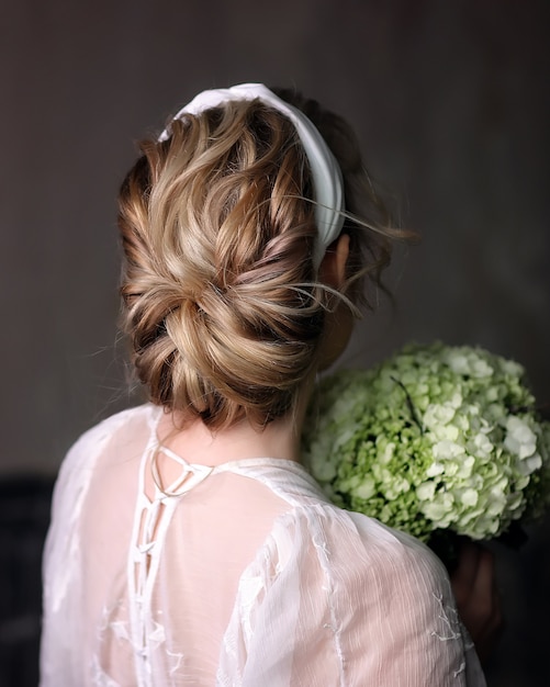 Esbelta novia de espaldas con un vestido de novia en el estudio. Cabello para la boda.