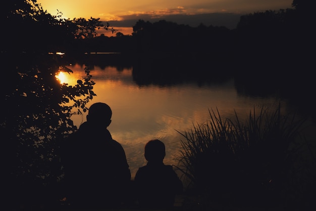 esboço de um menino com o papai ao pôr do sol no lago