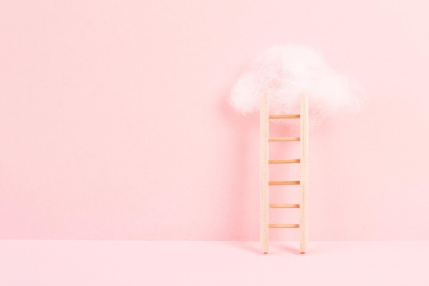 Escada com uma nuvem no topo, fundo cor de rosa rosa, espaço de cópia, sonhando com sucesso, criativo