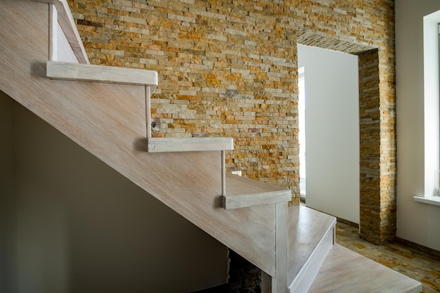 Escada contemporânea de madeira elegante dentro do interior da casa do loft. corredor moderno com paredes decorativas de tijolos de pedra calcária e escadas de carvalho branco.