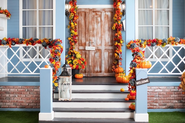 Escadaria de entrada da casa decorada para o halloween, flores de outono, folhas e abóboras.