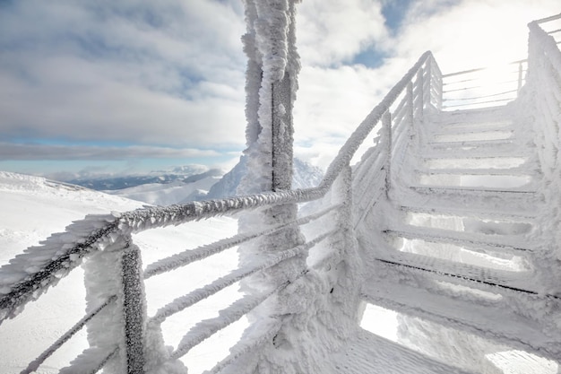 Escadas cobertas de neve e gelo, com forte luz de fundo do sol no fundo, ilustrando o frio extremo no inverno. Jasna, Eslováquia.