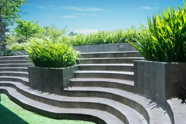 Escadas de concreto no parque com grama verde e plantas sob o céu azul filmadas ao ar livre