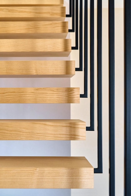 Escadas flutuantes Escadas de madeira de freixo com corrimão de metal preso à parede marrom e levando ao segundo andar dentro de uma casa moderna e elegante
