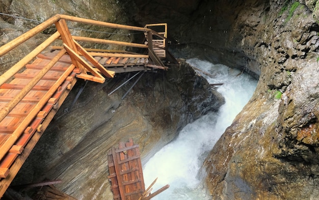 Escadas íngremes ao longo de cachoeira e pedras na Áustria