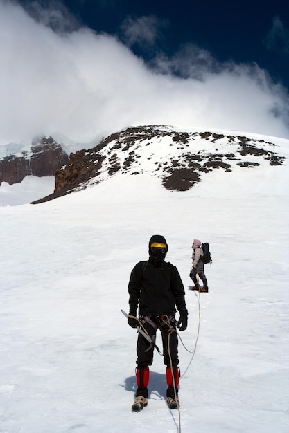 Escalador caminando por el glaciar nevado hasta la alta cumbre