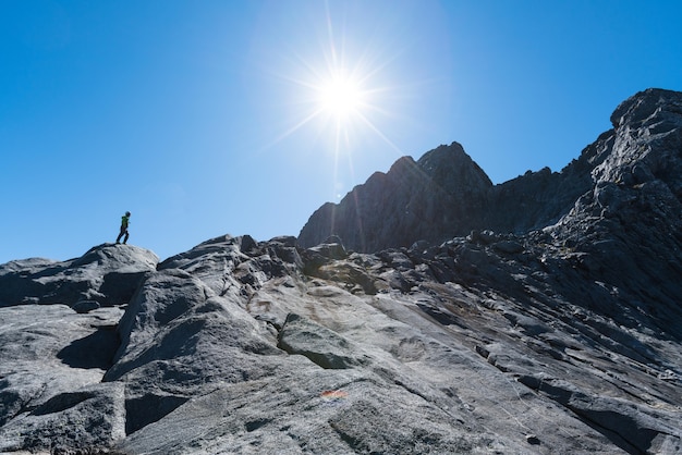 Un escalador se encuentra debajo del aspecto sureste de Sheerdown Peak, el Parque Nacional Fiordland