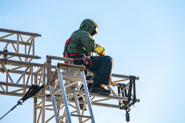 Foto escalador industrial en uniforme sentado ts en una estructura de edificio