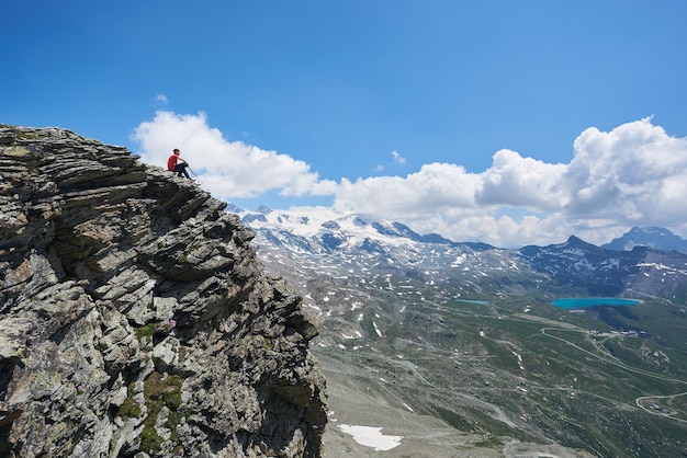 Escalador masculino sentado en la cima de la montaña