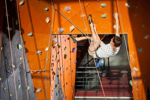 Foto el escalador se sube a la pared interior de escalada