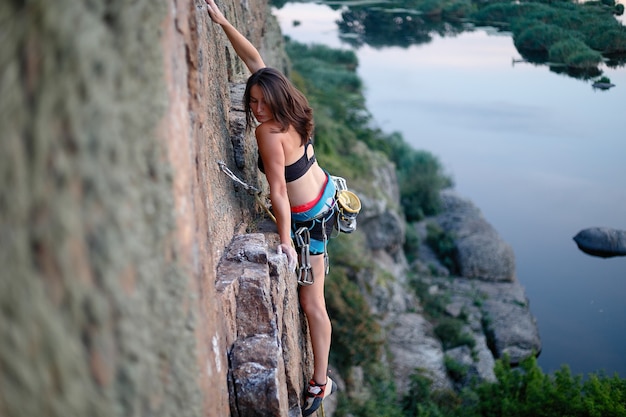 El escalador supera la desafiante ruta de escalada. Una niña sube a una roca. Mujer dedicada al deporte extremo. Pasatiempo extremo. pensativo en una roca