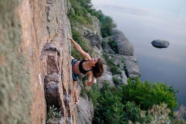 El escalador supera la desafiante ruta de escalada. Una niña sube a una roca. Mujer dedicada al deporte extremo. Pasatiempo extremo.