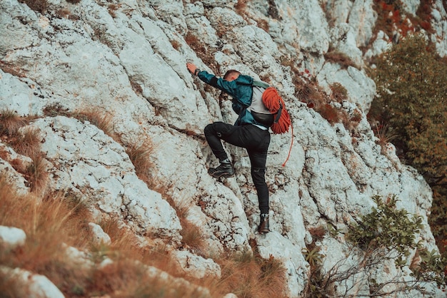 Escalador superando una difícil ruta de escalada en la montaña rocosa