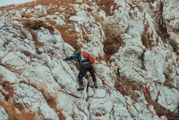 Escalador superando una difícil ruta de escalada en la montaña rocosa