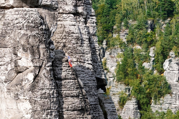 Un escalador en la superficie de la montaña en un bosque.