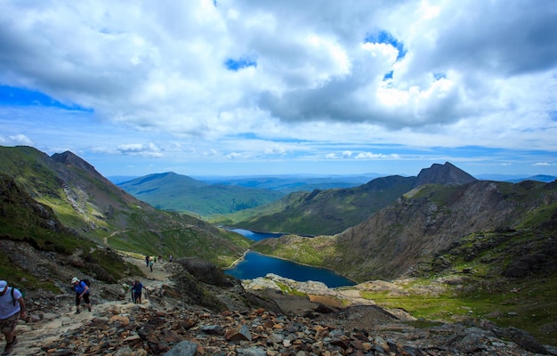 Los escaladores están ascendiendo Snowdon con vistas a Snowdonia y un lago de montaña U