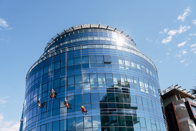 Foto los escaladores industriales están limpiando las ventanas del edificio desde el exterior