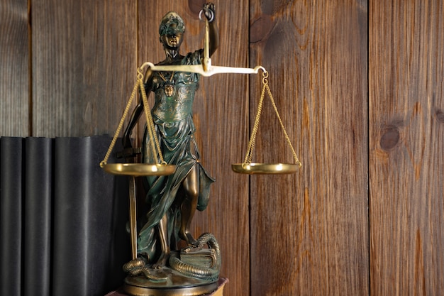Foto escalas da justiça, senhora justiça, conceito de biblioteca jurídica, livros de direito em segundo plano.