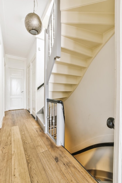 Una escalera en una casa con pisos de madera y blanco