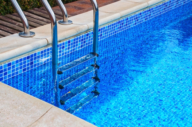Escalera de hierro en la piscina con azulejos azules.