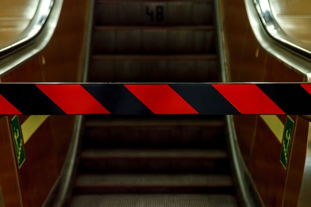 Escalera mecánica cerrada en metro. Vista inferior. Reparación de escaleras mecánicas, sin entrada, paso cerrado. Rayas rojas y negras en barrera prohibitiva. La escalera mecánica se detuvo. Espacio para su etiqueta y publicidad