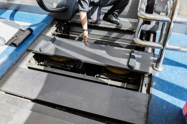 Foto escalera mecánica en grandes almacenes o aeropuerto fijación por técnico para pasajeros