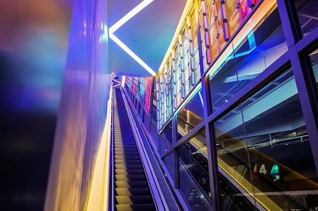 Escalera mecánica con luz LED al lado de la tecnología tema abstracto de luz de neón colorido